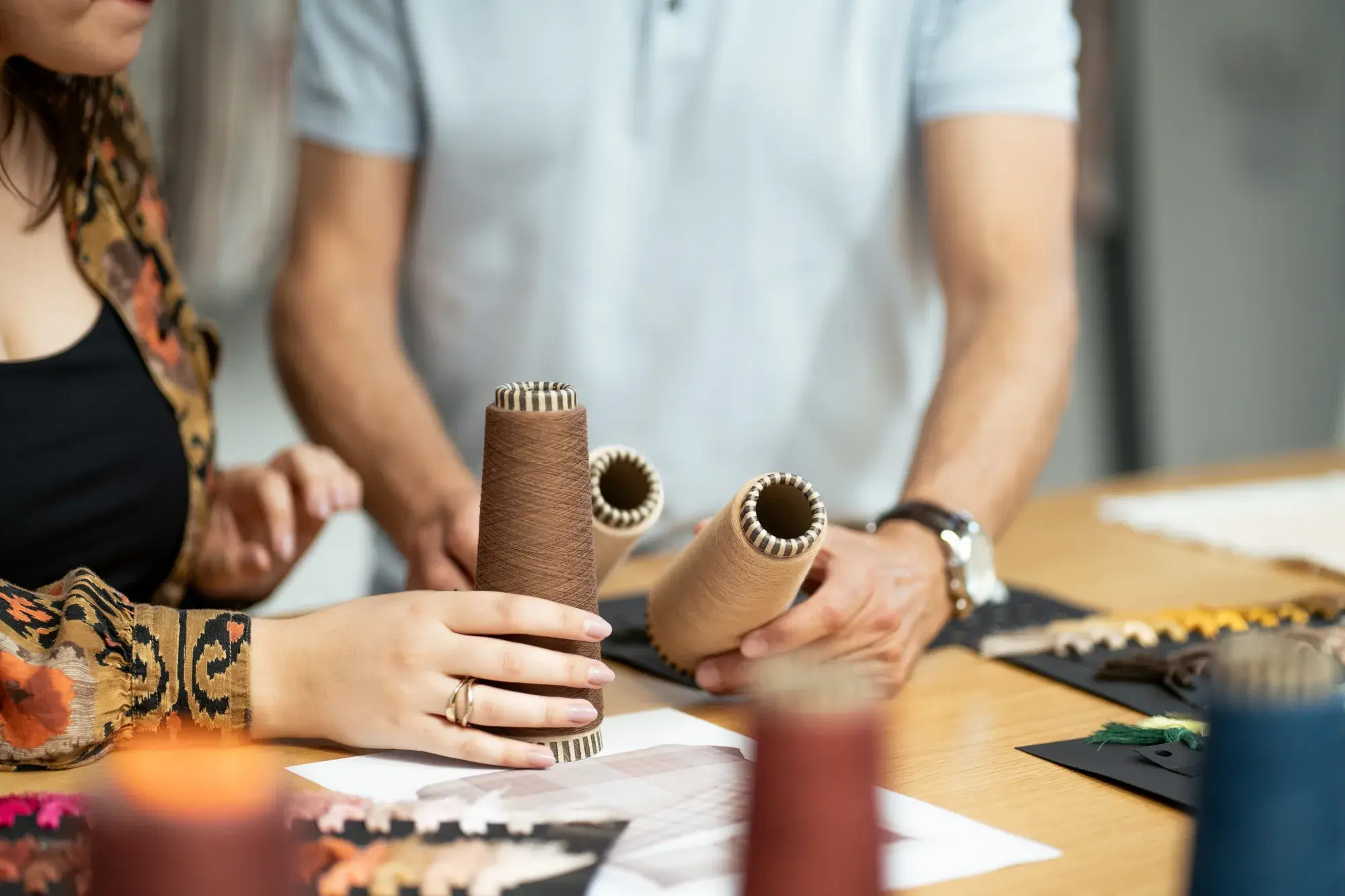 Hands working with yarn cones on the production floor